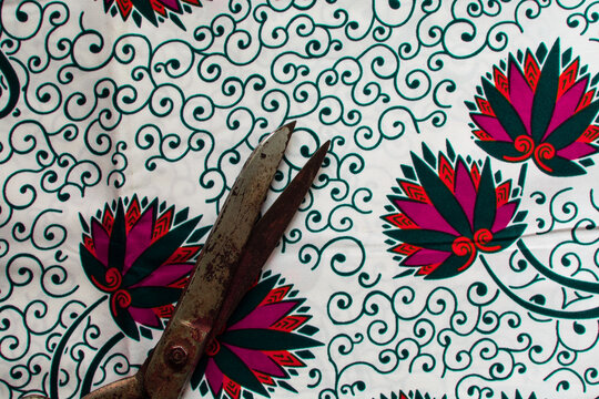 Top view of tarnished silver scissors on ankara fabric, large antique tailor scissors and ankara material on a table
