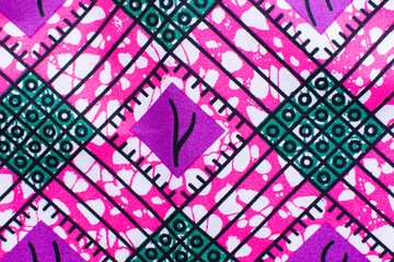 close up view of pink ankara fabric, flatlay of nigerian wax cloth with designs, spread out pink...