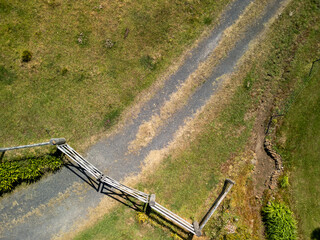 Aerial view of rural farm gate and gravel driveway in open green countryside