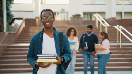 African American student holding books and giving thumbs up