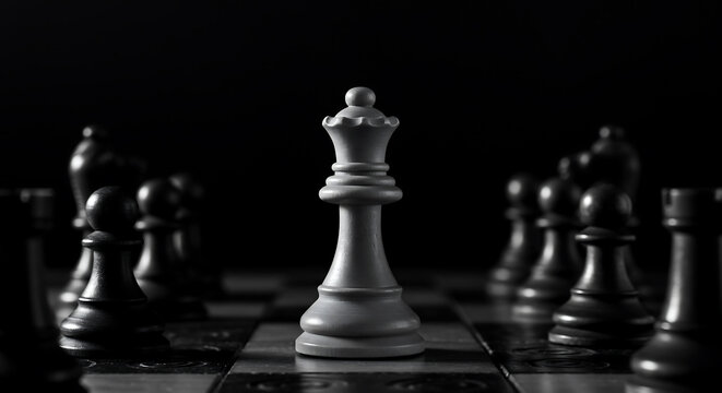 Dramatic black and white photograph of a chess queen piece surrounded by dark chess pieces