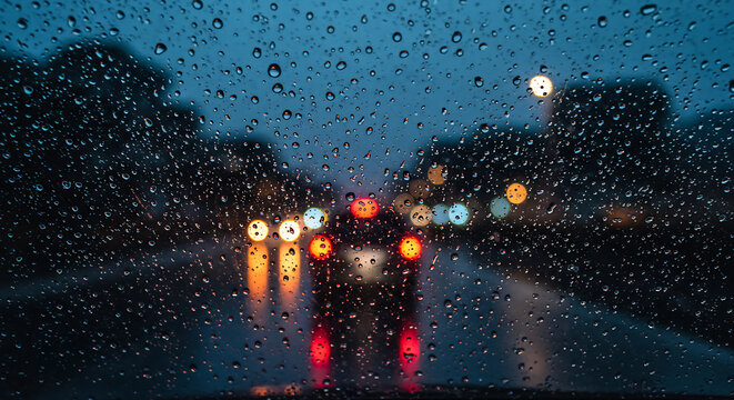 Rainy night driving scene. Raindrops on car windshield, blurred city lights and traffic create a moody, atmospheric scene - Powered by Adobe