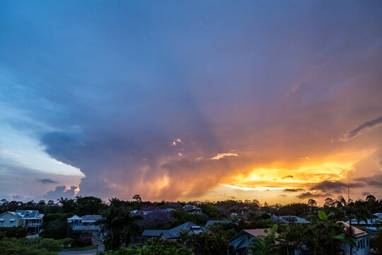 Colourful sunset storm clouds approaching suburban houses.