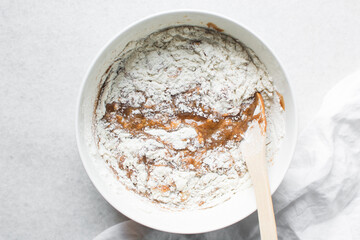 overhead view of brown sugar cookie dough being mixed in a white bowl, process of making fresh sugar cookies