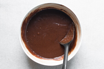 Overhead view of red velvet brownie batter being mixed in a white bowl, process of making red velvet brownies