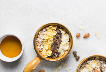 Top view of homemade granola mix in a brown terracotta ramekin, prepping healthy granola breakfast bowl