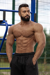 athletic man with a muscular build poses on a sports ground. He looks focused and confident...