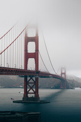Golden Gate Bridge tower emerging through thick coastal fog over the quiet bay.
