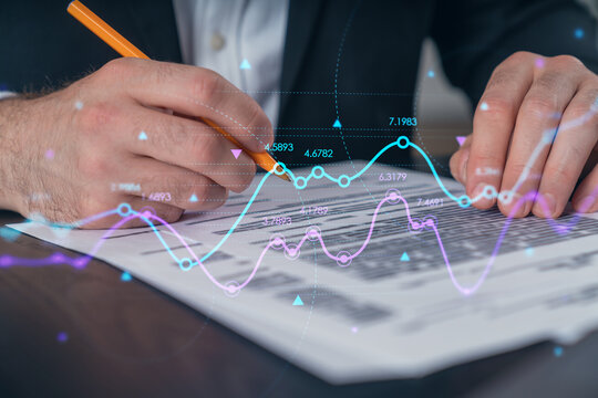Businessman in formal wear taking notes signing contract at office workplace. Concept of important working moments, document sign, working process, concentration. Hands shot. Financial charts hologram
