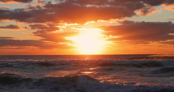 Scenic sunrise over the sea horizon and tropical island beach, the sun rising over the water surface