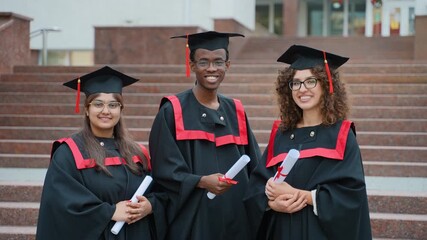 Multiethnic university graduates smiling with diplomas