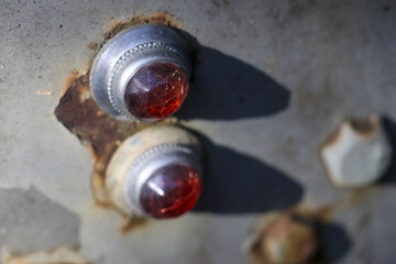 Macro view of two red glass reflectors on rusty, old metal surface. aged and weathered texture...