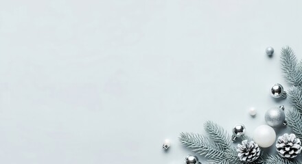 Elegant silver and white Christmas decorations with frosted fir branches, baubles, and pinecones on a light blue background with copy space
