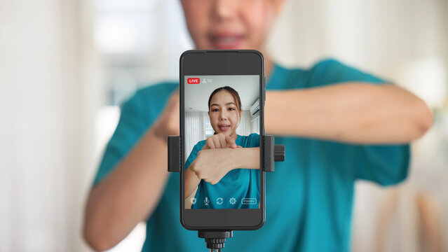 Young adult woman asia people anti aging expert modern nurse live talk video call selfie camera mobile phone app mental health care Online digital virtual asian vlogger filming hand wrist pain physio.