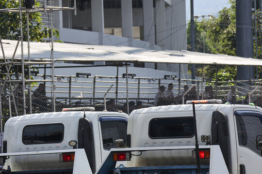 Row of white police vans parked on city street during an operation. This tense scene depicts authority and law enforcement with official transportation vehicles