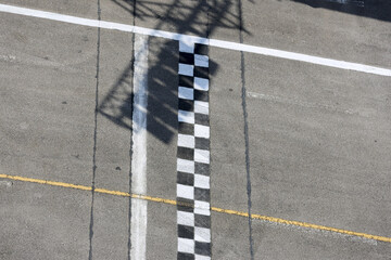 Aerial view of black and white checkered finish line on racetrack. symbol of winning race or competition, achieving goal. asphalt track represents sport and speed