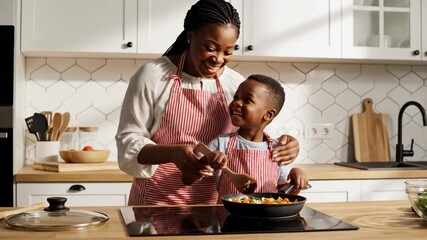 Happy mother and son cooking healthy meal together in modern bright kitchen.