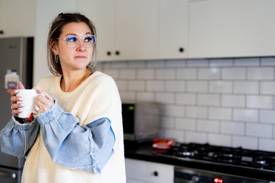 Woman holding a mug while standing in the kitchen