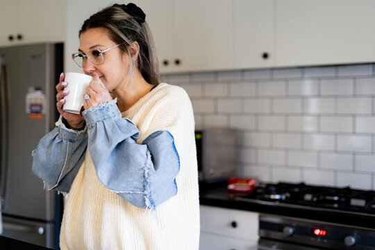 Woman holding a mug while standing in the kitchen