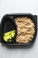 Overhead view of  a healthy rice bowl in a plastic plate, top view of rice, diced cucumber avocado amd fish in a bowl, yop view of a healthy rice bowl