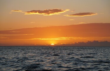 Horizon line view featuring intense orange and yellow hues in the low-hanging clouds during sunset near Madeira Beach, Florida, U.S.A