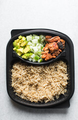 Overhead view of  a healthy rice bowl in a plastic plate, top view of rice, diced cucumber avocado amd fish in a bowl, yop view of a healthy rice bowl