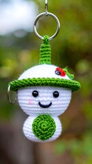 Crocheted doll with happy face, in white and green, hangs on ring, bokeh background
