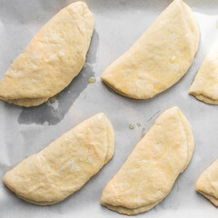 Coco bread dough on a parchment lined baking tray, process of making jamaican coco bread