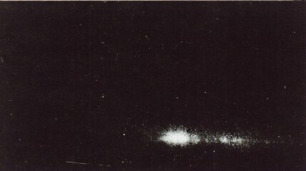 Fototapeta premium A dark image featuring a faint cluster of light, possibly depicting celestial phenomena or astrophotography.