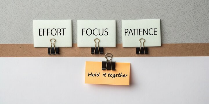 Motivational desk display with notes emphasizing effort, focus, patience, and a reminder to hold it together for productivity and success