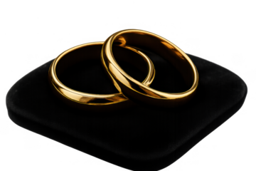 Gold wedding bands symbolizing love and commitment, resting on a black velvet cushion, transparent background