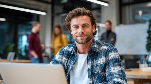 Modern office workspace with attractive male model at laptop, new fashion outfit, unique pose, colleagues collaborating, professional scene, corporate teamwork, productivity.