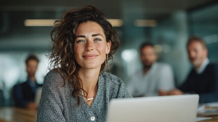Modern office with attractive female model using laptop, confident posture, new outfit, colleagues collaborating behind, professional environment, teamwork, corporate business productivity.