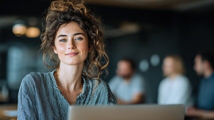 Attractive model woman working at laptop in contemporary office, confident posture, new clothes, colleagues collaborating behind, professional workspace, corporate teamwork, productivity.
