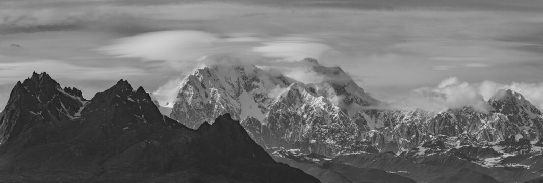 This black and white Alaska summer mountain panorama features spaceship clouds (lenticular clouds) hovering around Mount Foraker in the Alaska Range. - Powered by Adobe