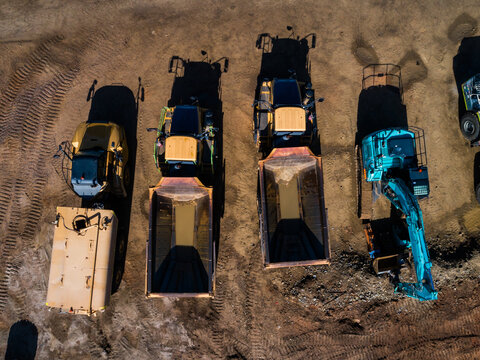 Heavy earthmoving machinery parked on highway road construction worksite from aerial perspective
