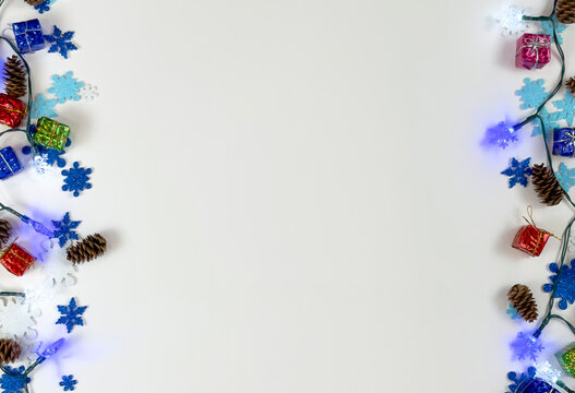 Winter holiday border with lights pinecones and colorful decorations on white background - Powered by Adobe