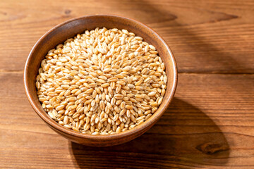 top view flat lay overhead malt barley grain beer whole in wood plate on wood table background. pile of malt barley grain beer whole. heap of malt barley grain beer whole food background