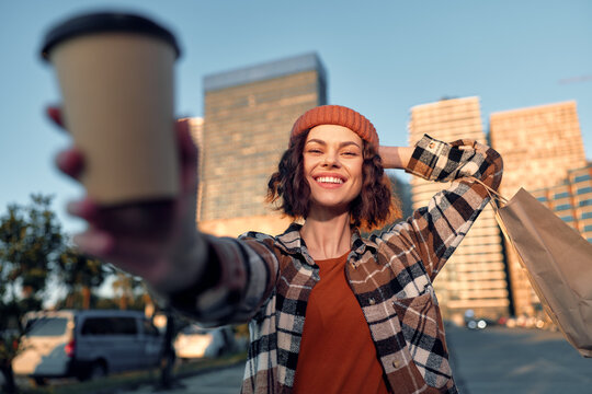 Woman holding coffee cup and shopping bag in urban street, smile and candid lifestyle moment with authenticity and golden hour glow, mindful living and emotional storytelling.