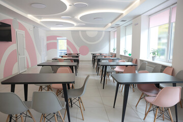 Tables with chairs in stylish room at school