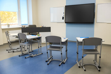 Stylish classroom with desks, chairs and tv at school