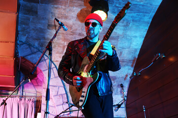 Handsome man playing electric guitar on stage, low angle view