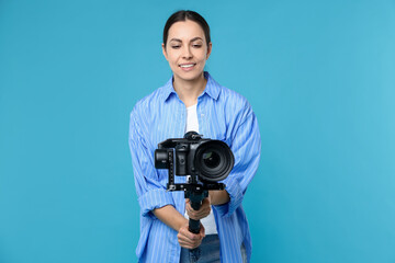 Obraz premium Videographer using gimbal stabilizer with camera on light blue background