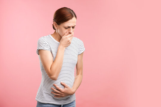 Pregnant woman suffering from nausea on pink background. Space for text