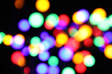 Fototapeta premium Blurred view of bright Christmas lights on dark background, bokeh effect