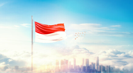 Indonesia flag wavering in beautiful clouds with building skyline. The flag with drone shot in...