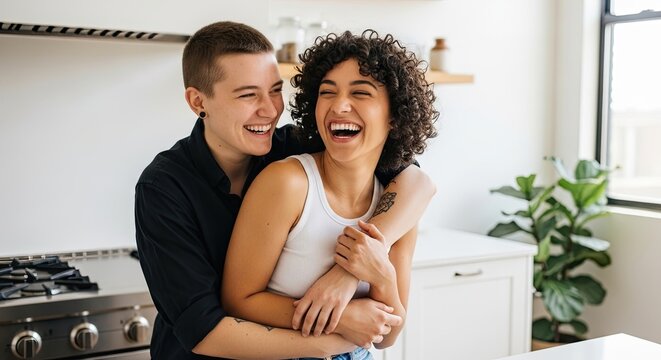 Happy couple embraces and laughs together in a bright modern kitchen
