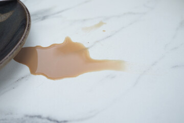 Coffee spill on marble surface near a plate