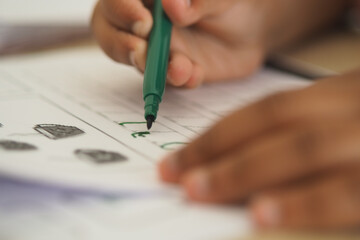 Young child practicing writing with green marker on paper
