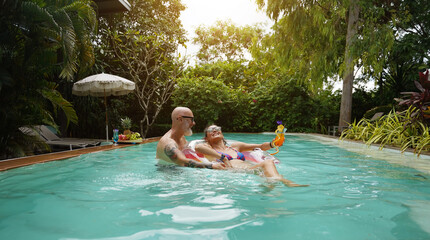A man and a woman are having fun and drinking cocktails in the pool.